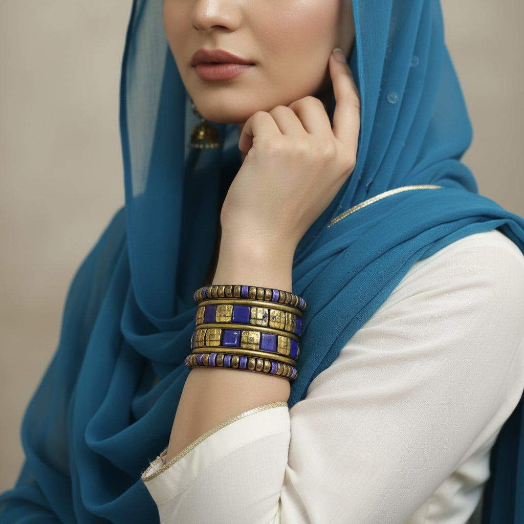 Set of gold and purple bracelets on a gray cushion against a dark background