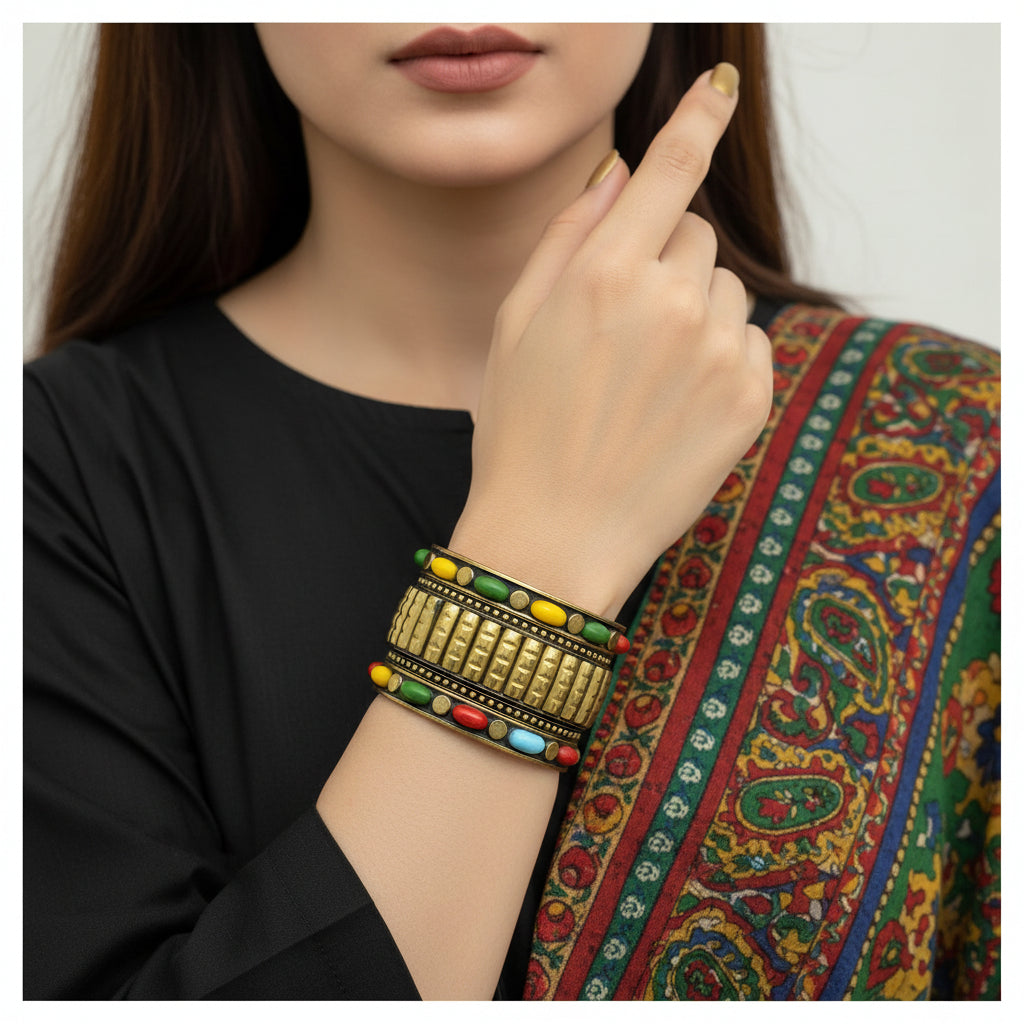 Gold bracelet with colorful beads on a gray stone surface