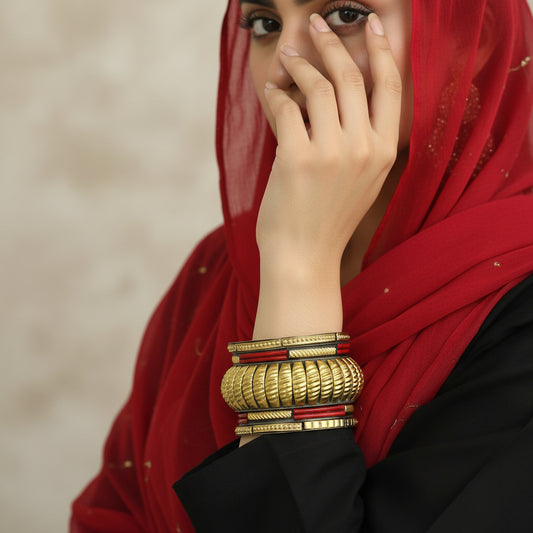 Gold bracelet with red accents on a gray stand against a dark background