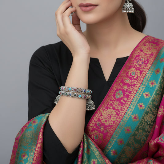 Decorative hoop earrings with colorful gemstones on a black stand against a dark background