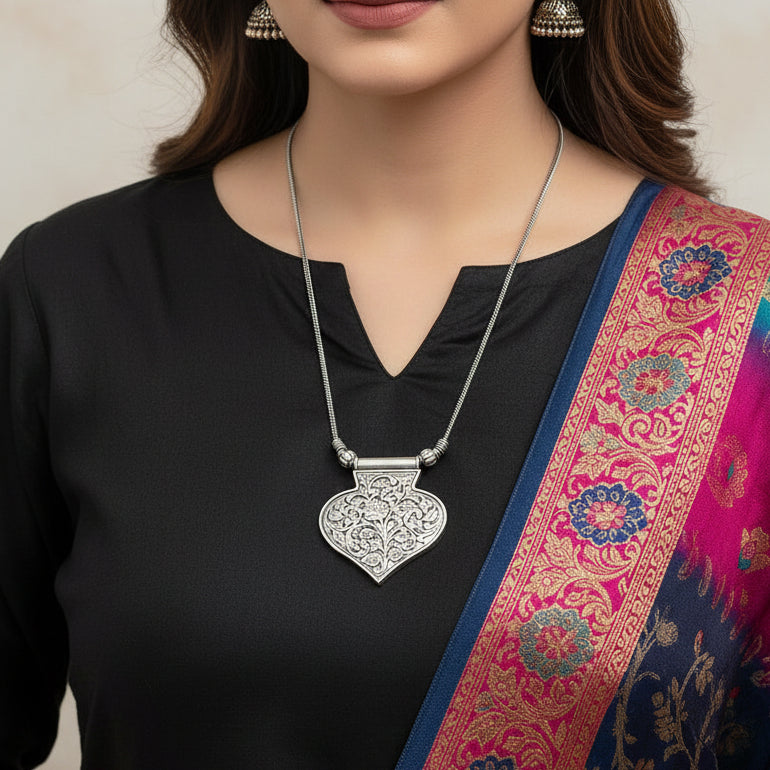 Silver necklace with an intricate pendant on a gray background, featuring the brand 'SAHELL'.