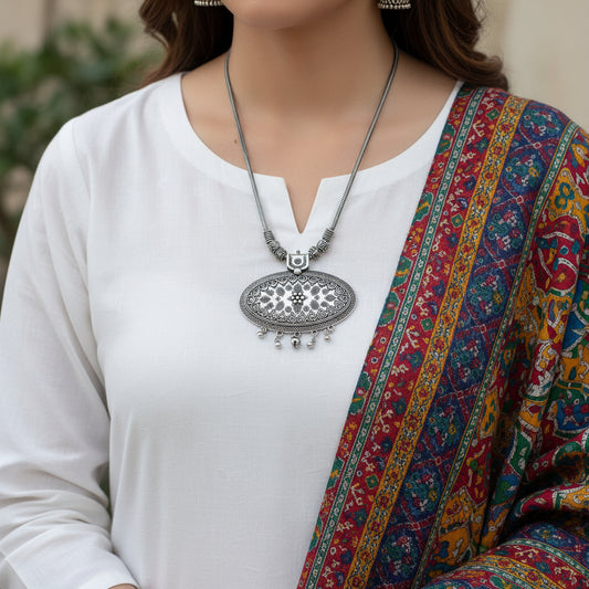 Silver necklace with intricate pendant on a dark background