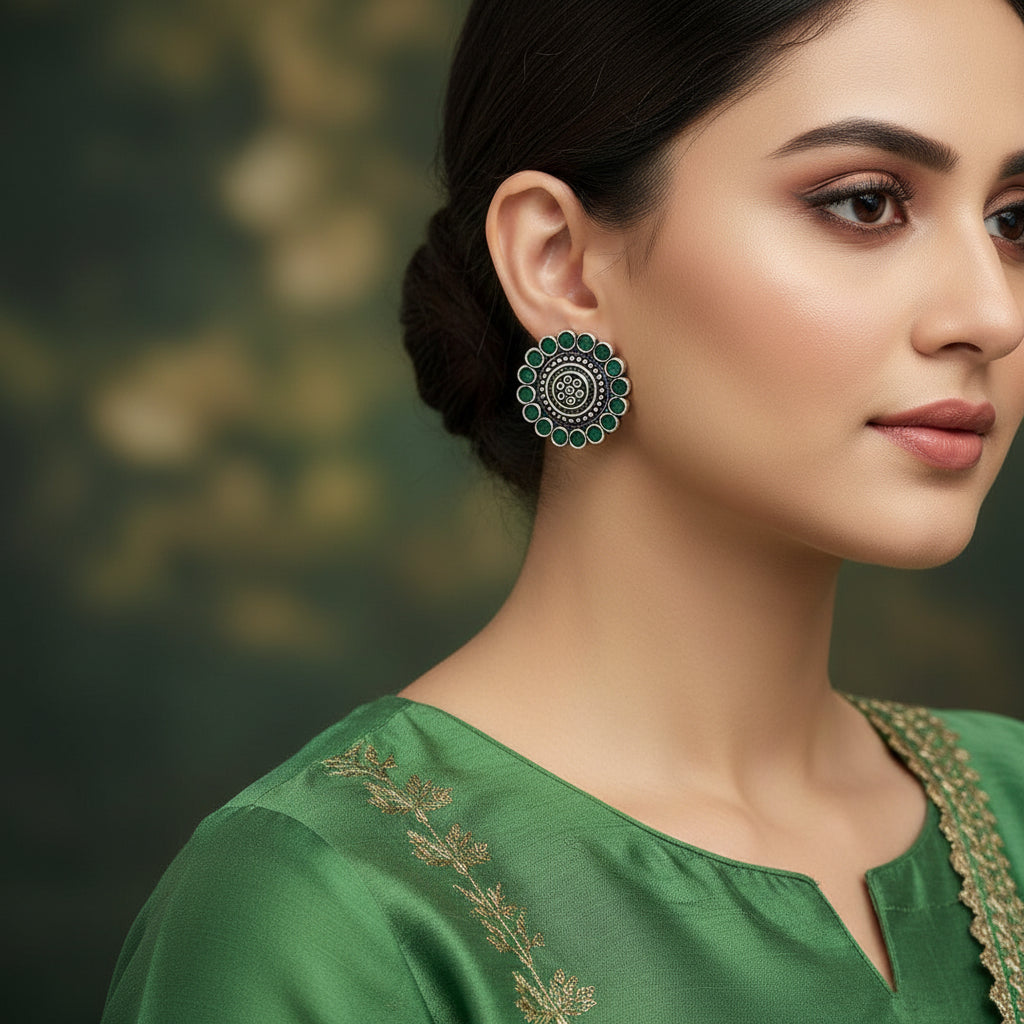 Pair of silver earrings with green gemstones on a black background