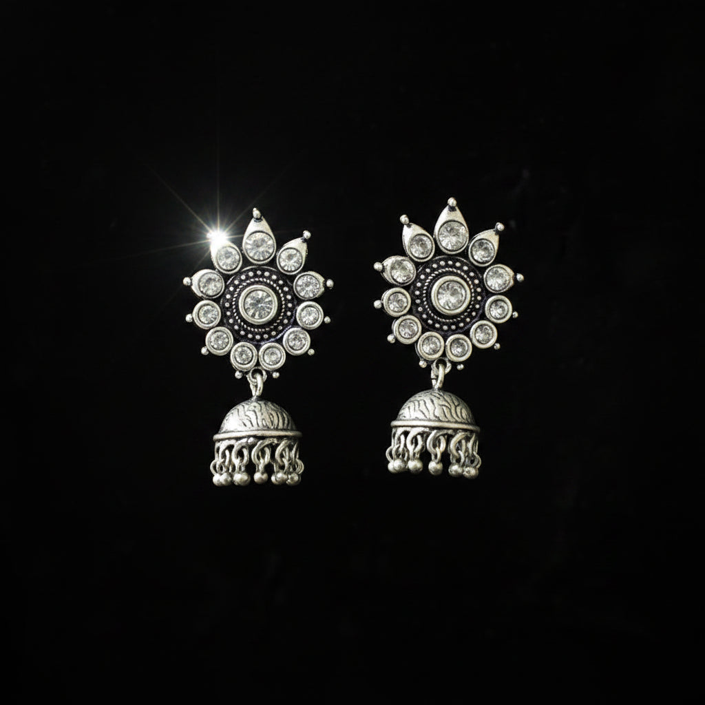 Pair of silver jhumka earrings on a black background