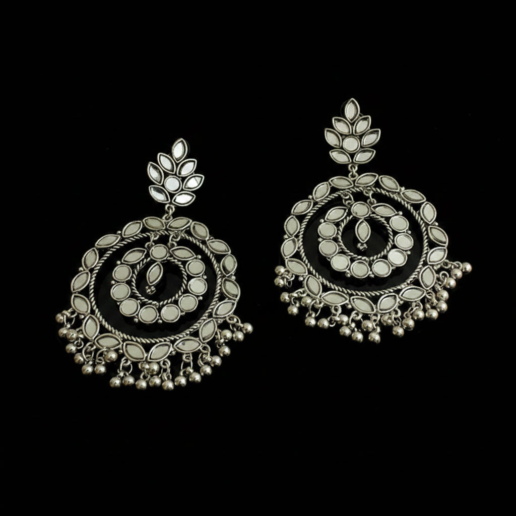 Pair of silver earrings with intricate designs on a black background