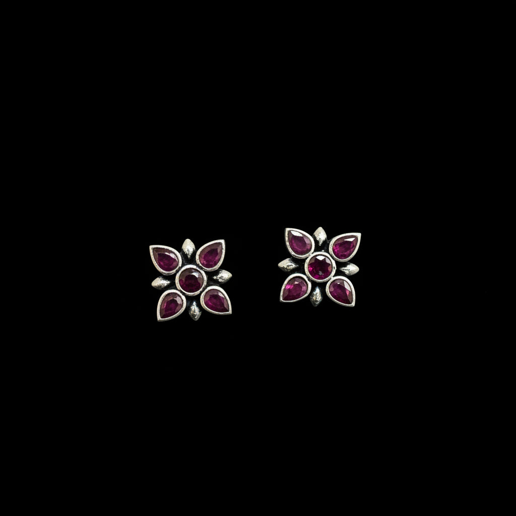 Pair of silver earrings with purple gemstones on a dark gray background