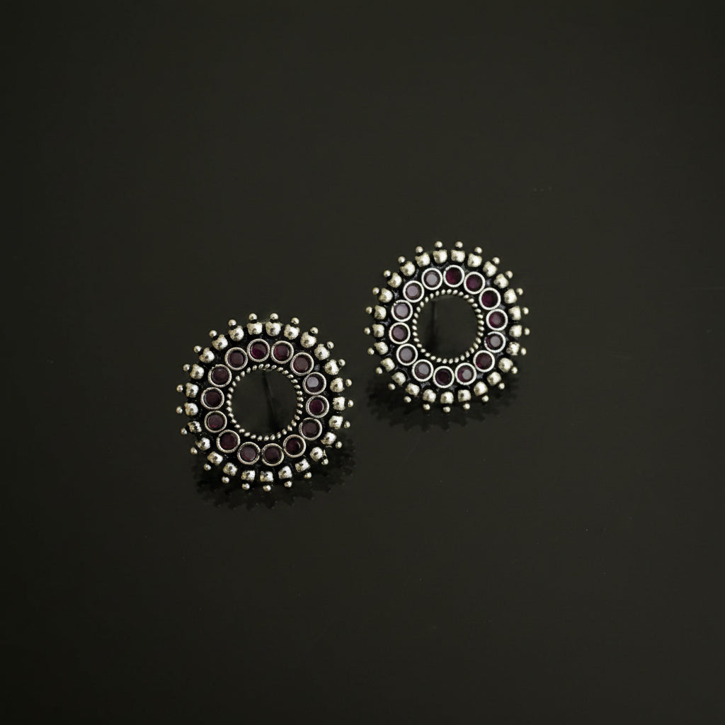 Pair of silver earrings with circular design on a dark background