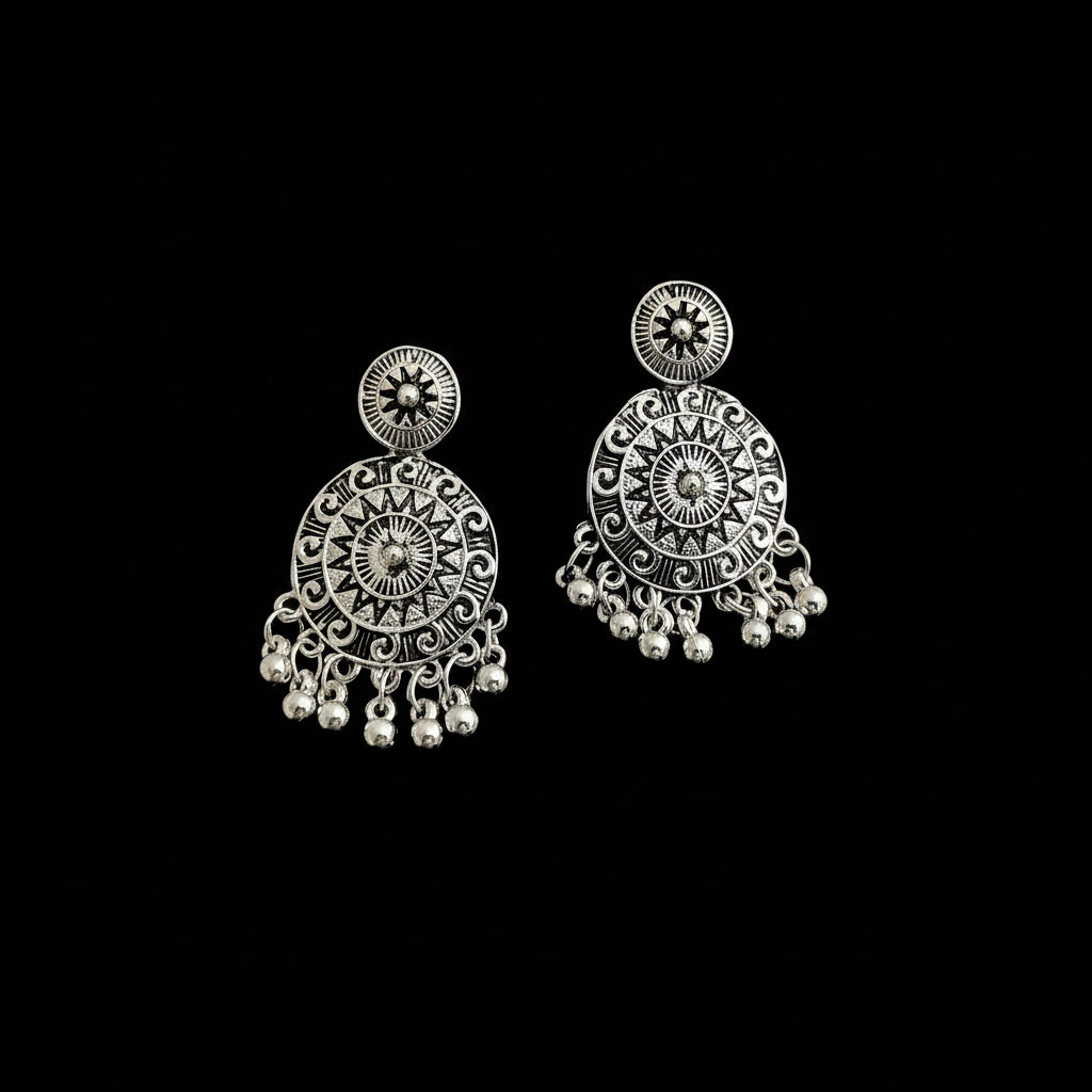 Pair of silver earrings with intricate designs on a black background