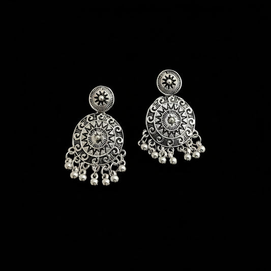 Pair of silver earrings with intricate designs on a black background