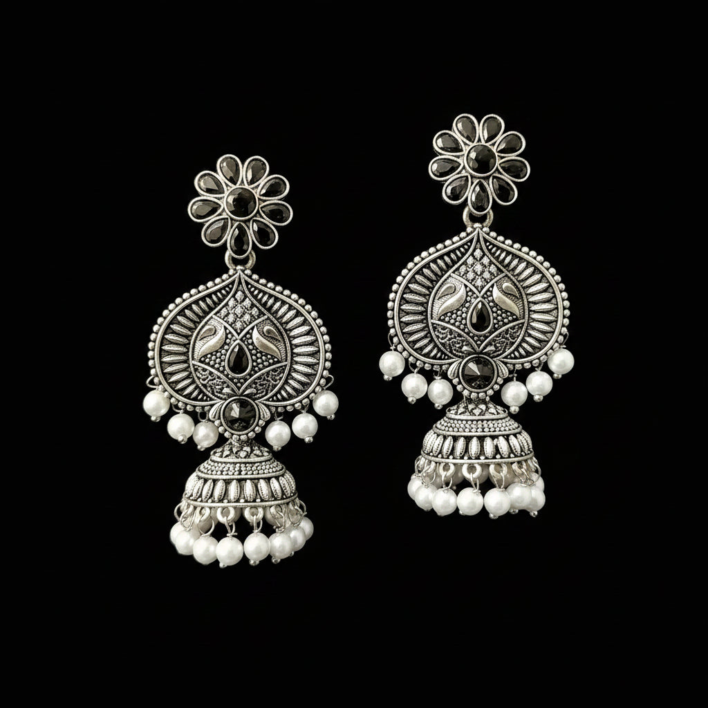 Pair of silver earrings with floral designs and pearl beads on a gray background