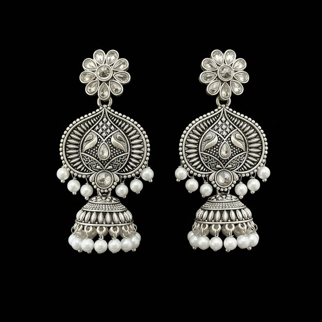 Pair of silver floral earrings with pearl beads on a gray stand.