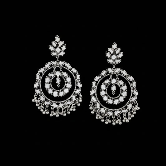 Pair of silver earrings with intricate designs on a black background