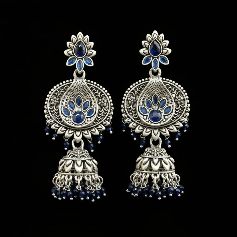 Pair of silver and blue earrings on a gray stand with a blurred background