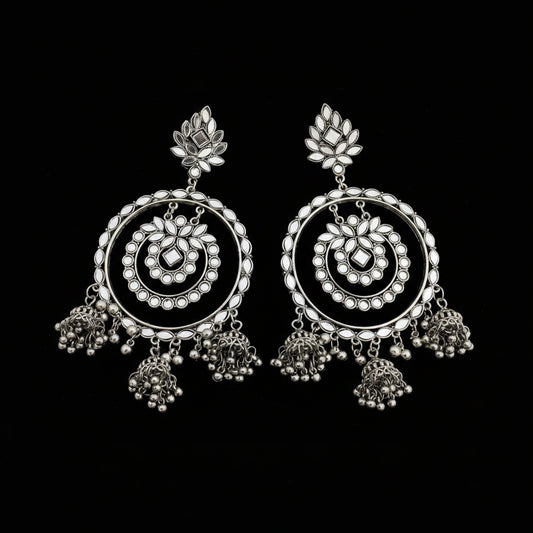 Pair of silver earrings with intricate designs on a dark background