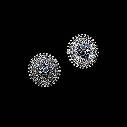 Pair of silver earrings with blue gemstones on a gray background