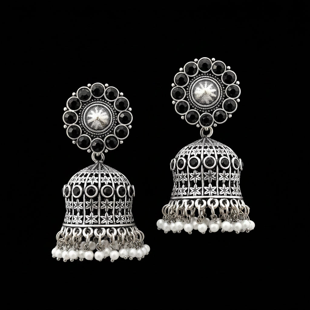 Pair of silver jhumka earrings with black stones and pearl accents on a gray stand.