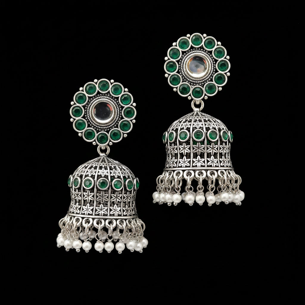 Pair of silver and green earrings on a gray stand with a blurred background