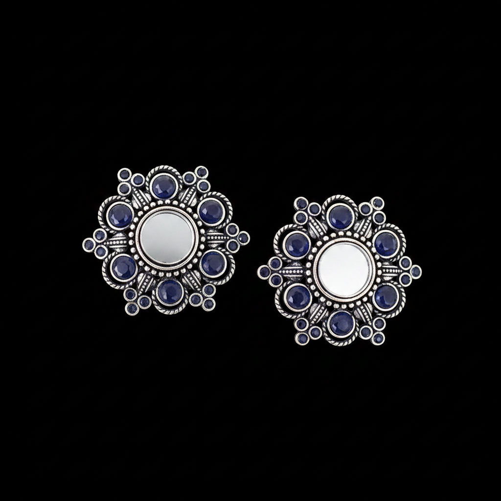 Silver earrings with blue stones on a gray background, branded 'Saheli'.