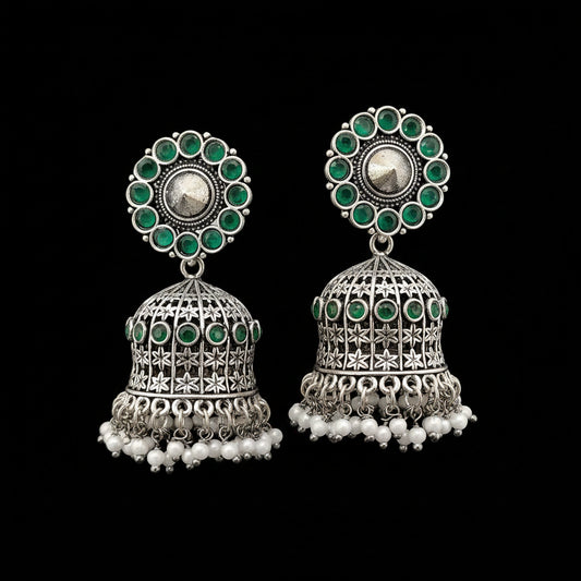 Pair of silver and green earrings on a gray stand with a blurred background