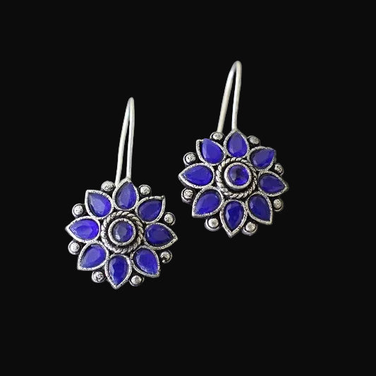Pair of blue flower-shaped earrings on a gray surface