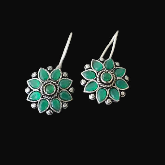 Pair of green floral earrings on a gray cushion