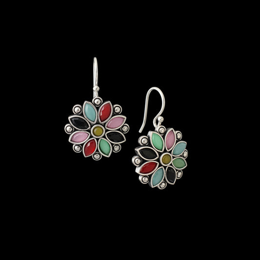 Colorful flower-shaped earrings on a gray stand against a dark background