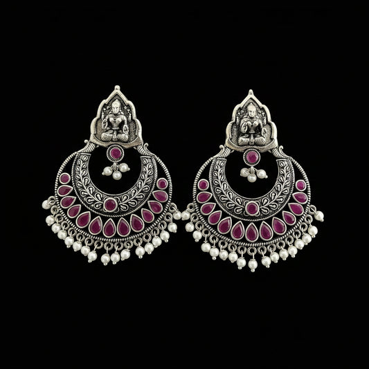 Ornate silver and pink earrings with 'Saheli' branding on a gray background