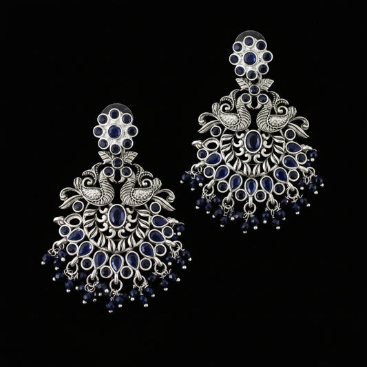 Ornate silver and blue earrings on a gray background