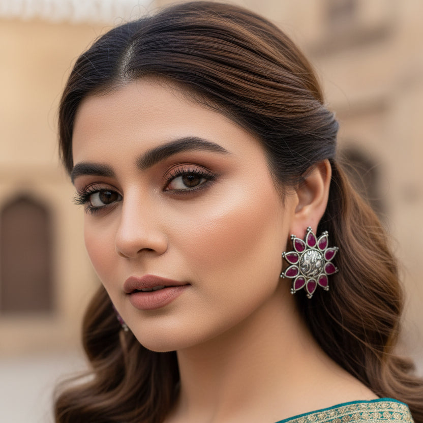 Pair of red and silver earrings on a blue surface with 'Al-Rawnaq' branding.