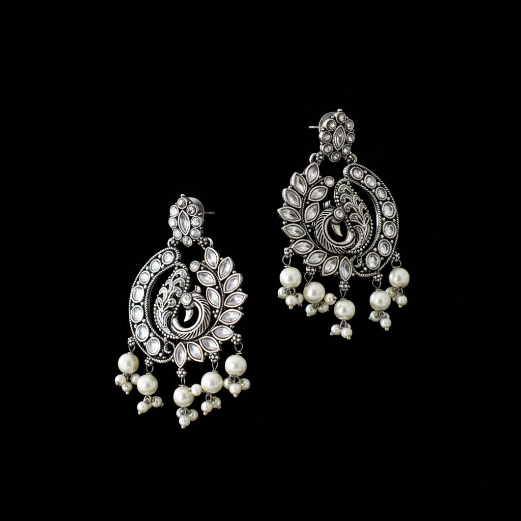 Ornate silver and pearl earrings on a dark background