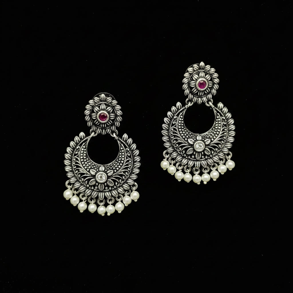 Pair of silver earrings with pearls and gemstones on a black background