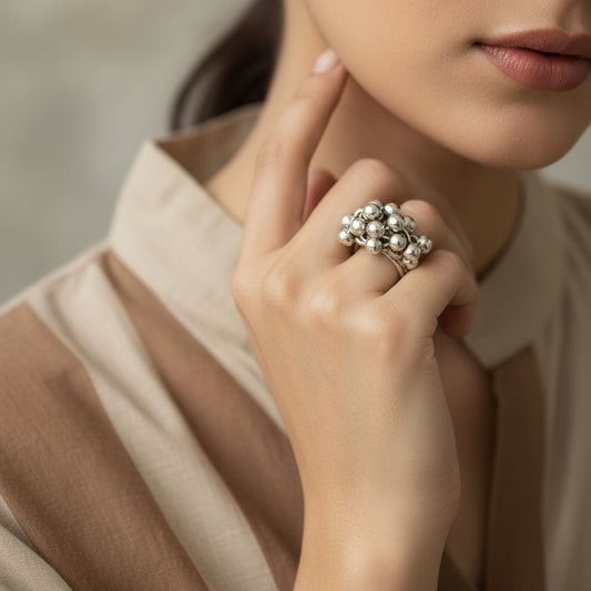 Silver ring on a black mannequin hand against a dark background