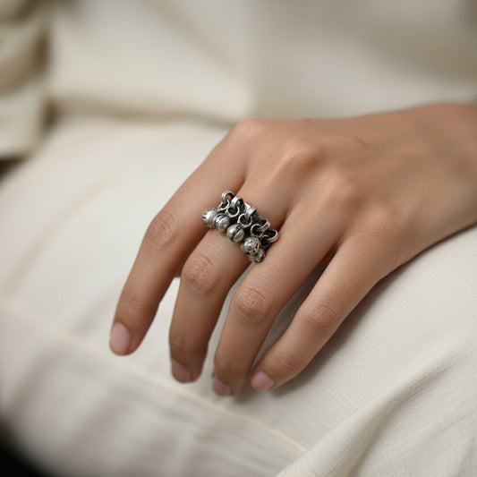 Silver ring with pearls on a black mannequin hand against a dark background