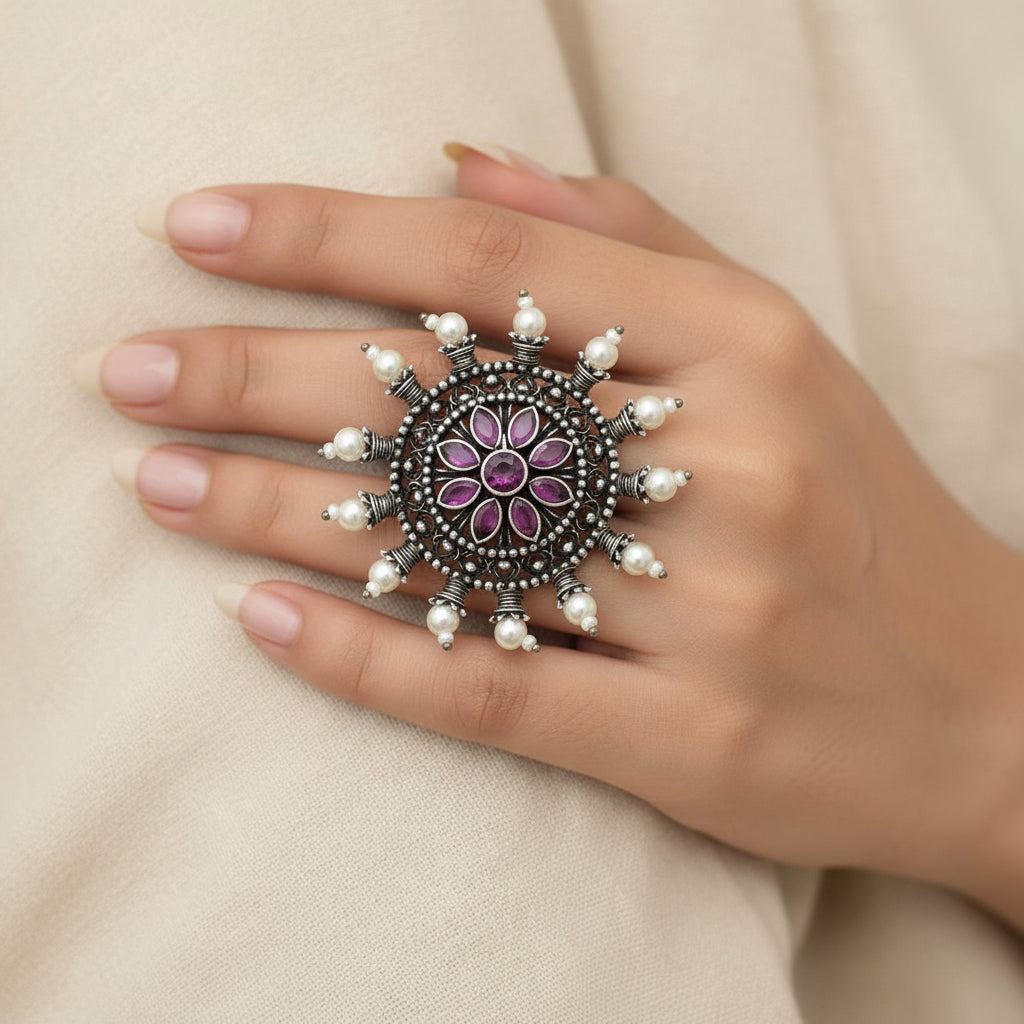 Jewelry item with purple center and pearl-like accents on a gray background