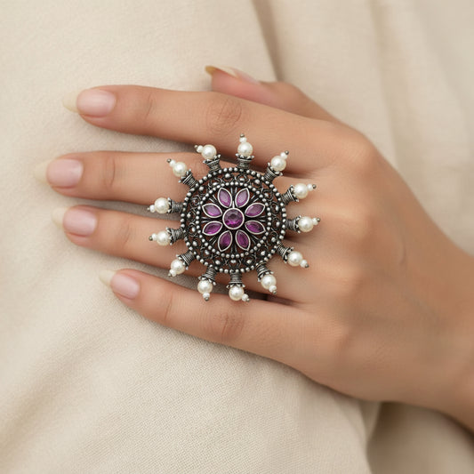 Jewelry item with purple center and pearl-like accents on a gray background