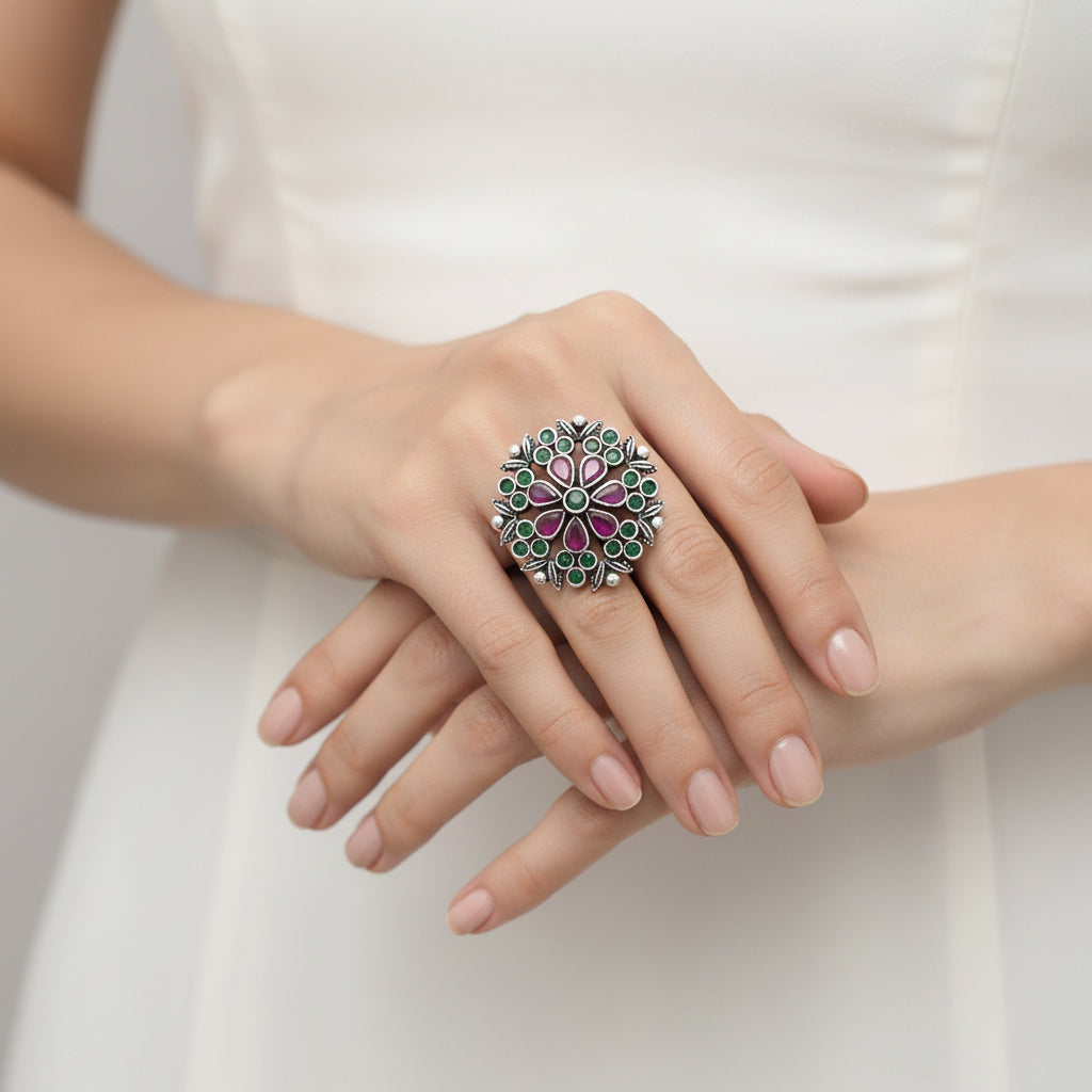 Silver ring with green and purple stones on a black mannequin hand, branded 'Saheli'.