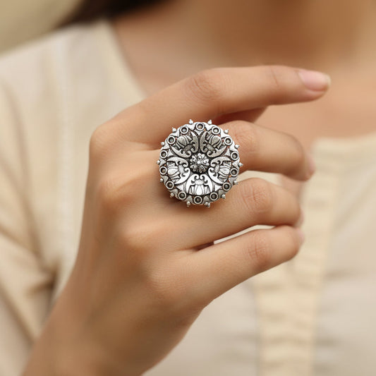 Silver ring with intricate design on a gray background