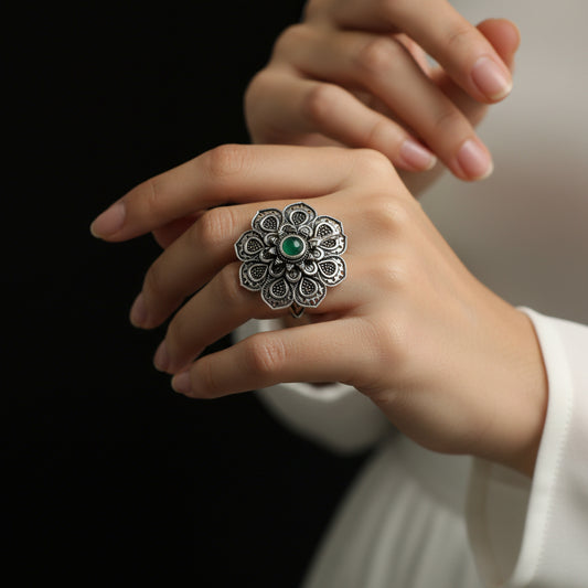 Silver ring with a green gemstone on a dark gray background