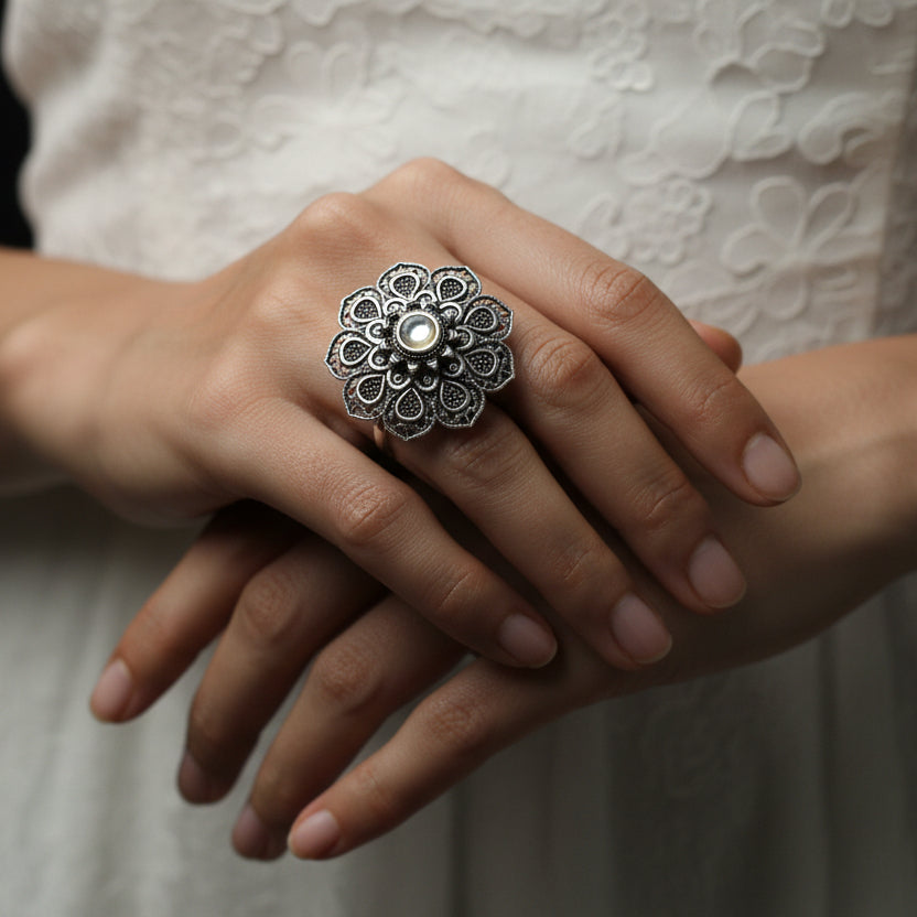Silver floral ring on a reflective gray surface
