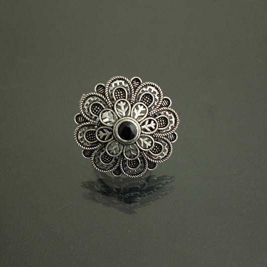 Silver floral ring with a black gemstone on a dark gray background
