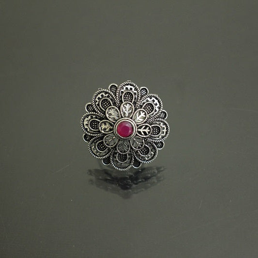 Decorative ring with a red gemstone on a dark gray background
