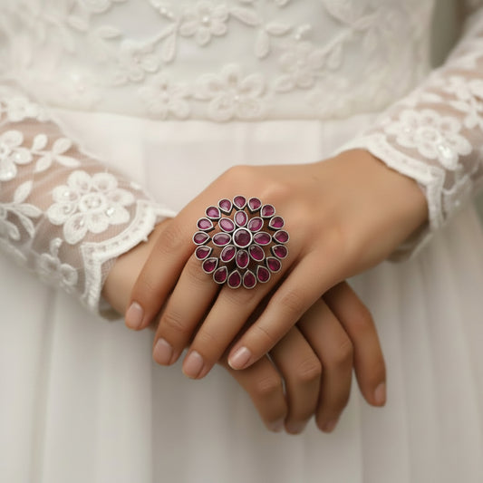 Ring with pink gemstones on a black mannequin hand against a gray background