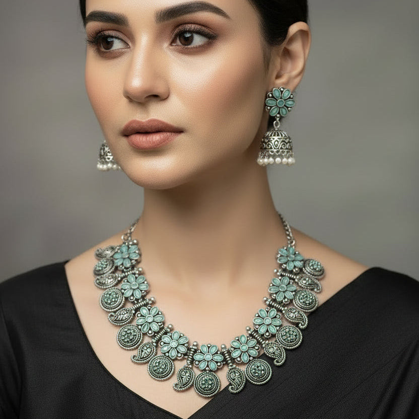 Silver necklace with floral designs and matching earrings on a gray background