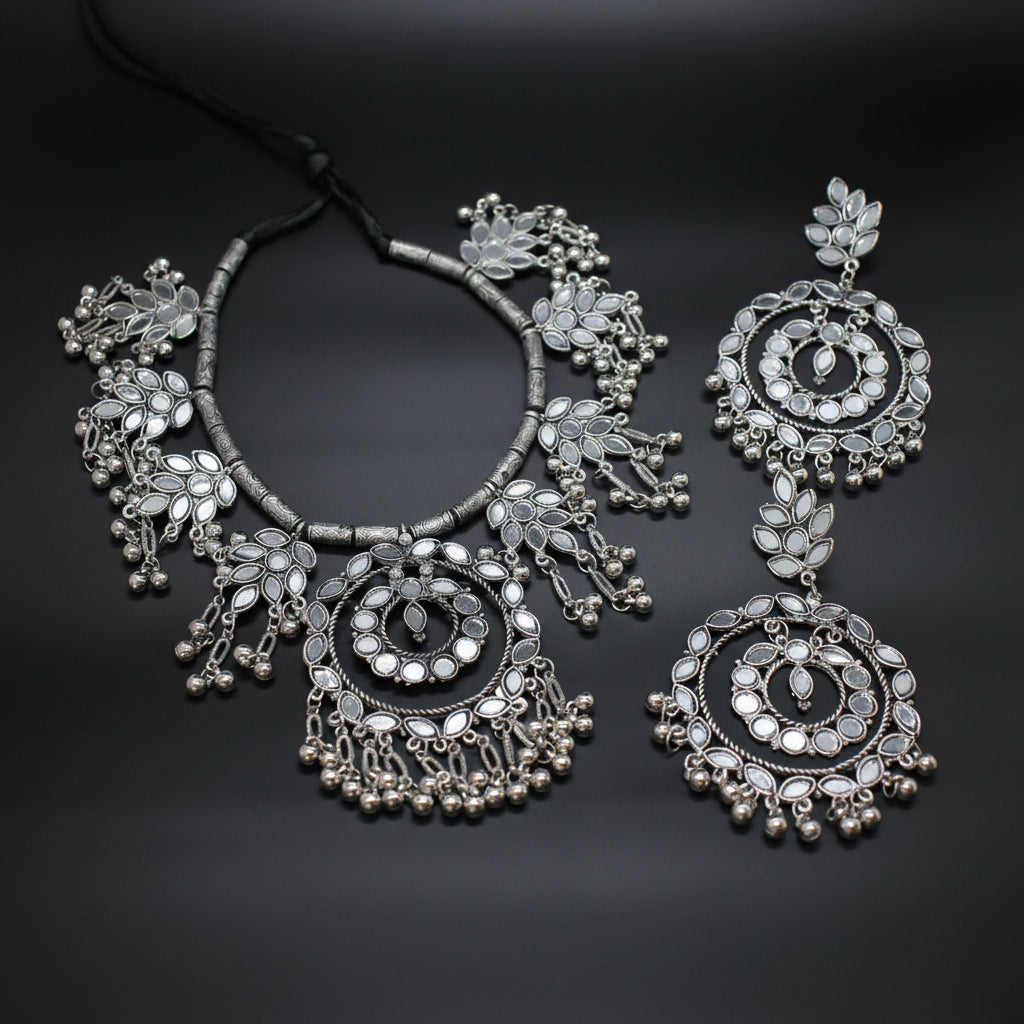 Silver necklace and earrings on a dark background