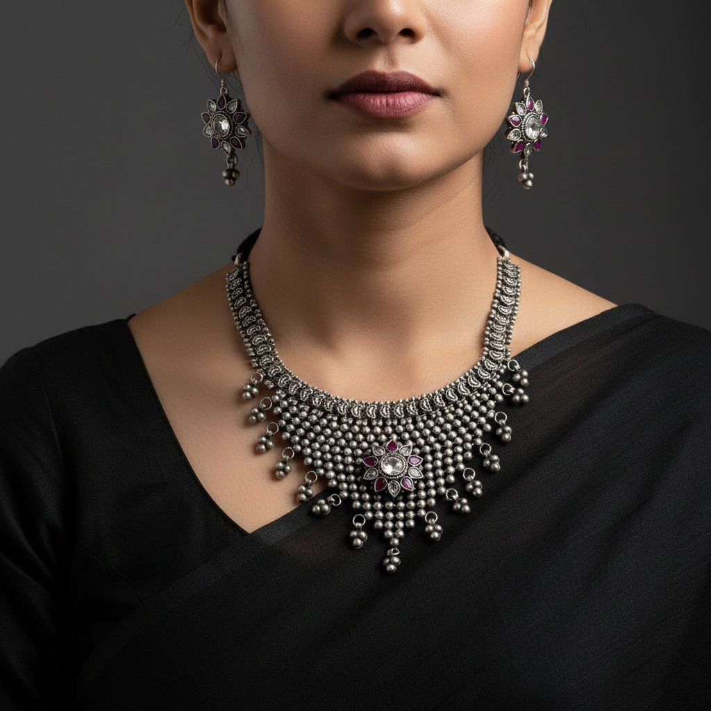Silver necklace and earrings with 'Saheli' branding on a gray background