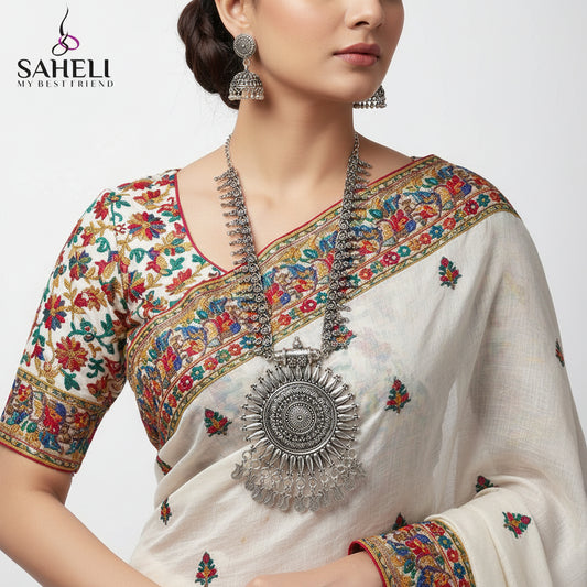 Silver necklace and earrings on a white background with 'SAHELI' branding.