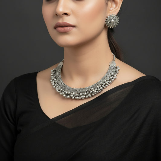 Silver necklace and earrings set with 'Saheli' brand logo on a dark background