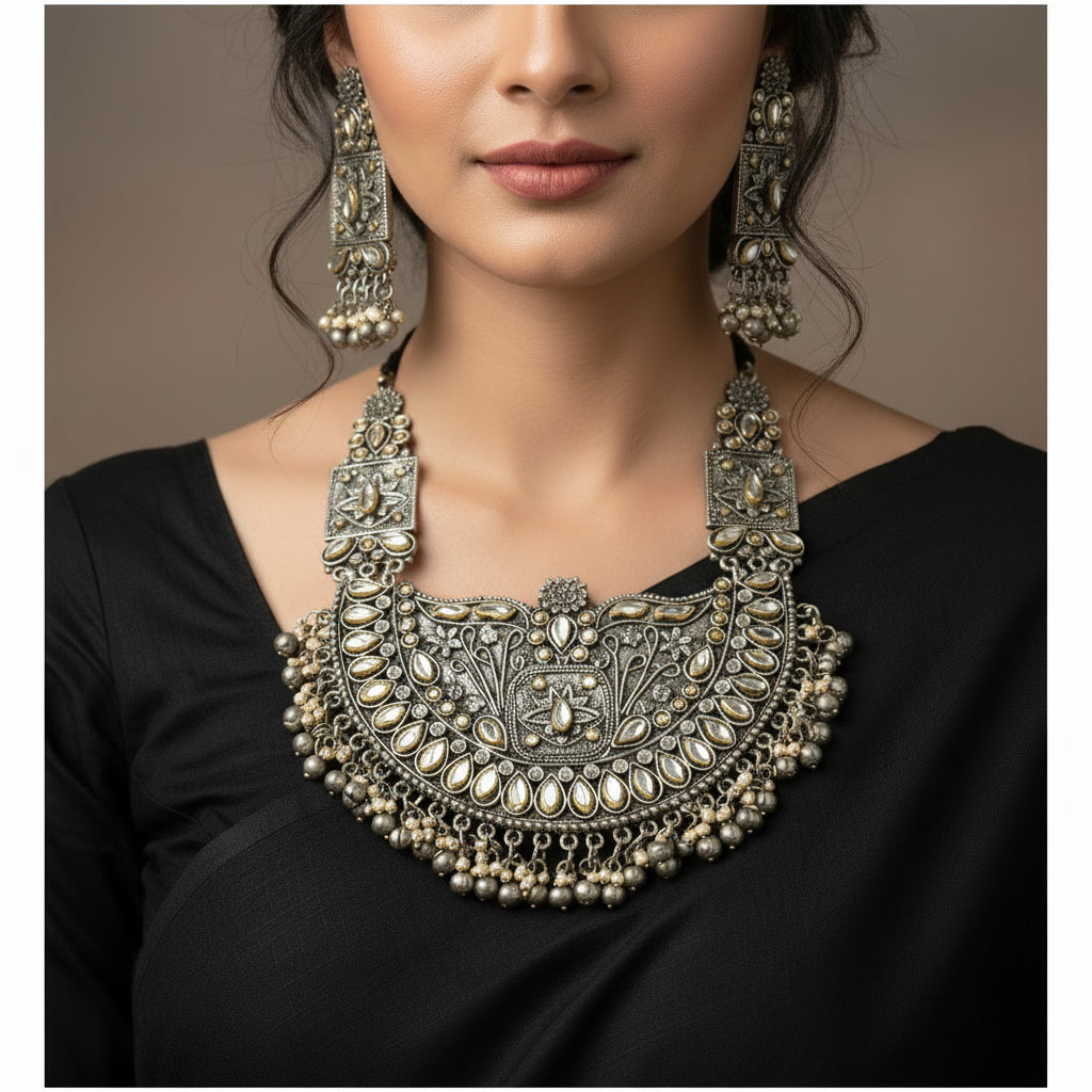Ornate silver necklace set with matching earrings on a white background, featuring the brand 'Saheli'.
