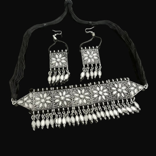 Ornate silver necklace and earrings set with 'Saheli' branding on a dark background