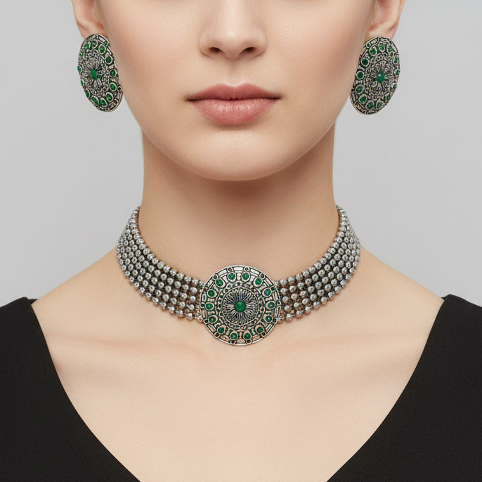 Silver necklace with green gemstones on a dark surface